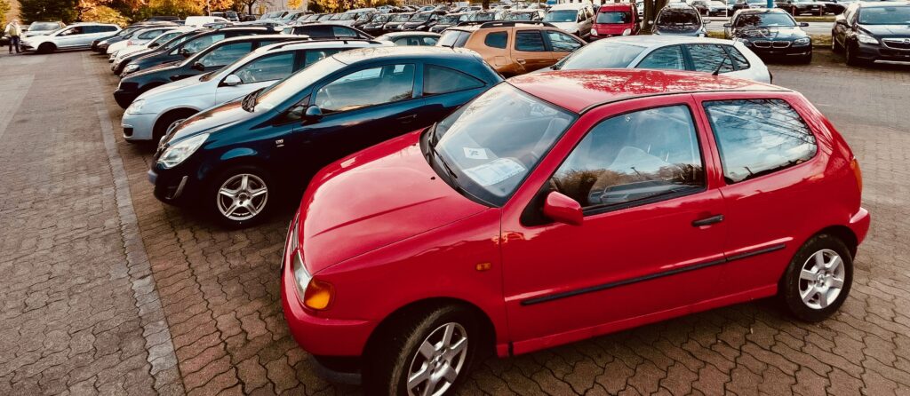 Roter Polo vorne und viele andere. Blick über den Gebrauchtwagen-Parkplatz des HOCO Automarkts am Schwabenring 104 in Minden im Herbst 2025.